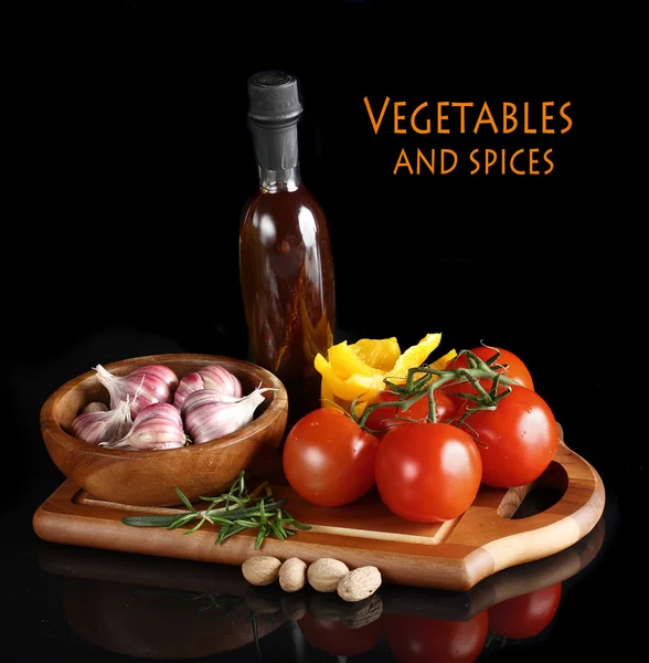 Tomatoes and garlic in wooden plate on black background. — Stock Photo, Image