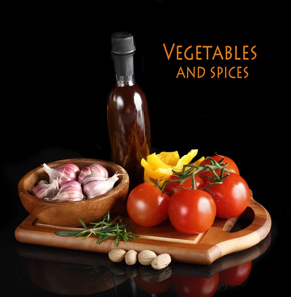 Tomates y ajo en plato de madera sobre fondo negro . — Foto de Stock