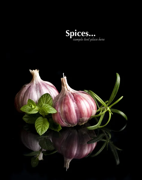 Tomatoes and garlic in wooden plate on black background.