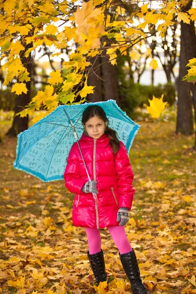 Девочка, веселись, играя с упавшими золотыми листьями — стоковое фото