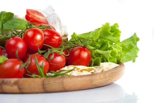 Свежие помидоры черри и салат в деревянной тарелке — стоковое фото