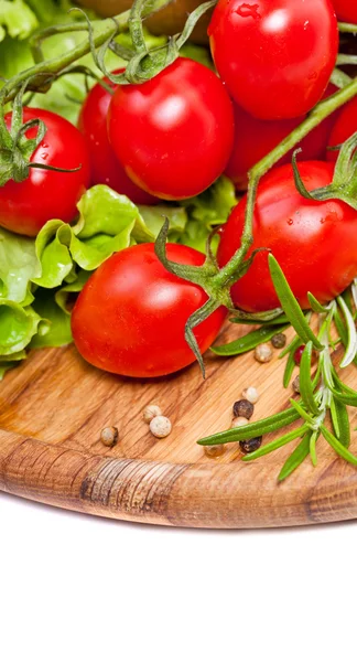 Pomodori ciliegini freschi e insalata in un piatto di legno — Foto Stock