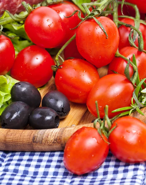 Fresh cherry tomatoes and salad in a wooden plate — Stock Photo, Image