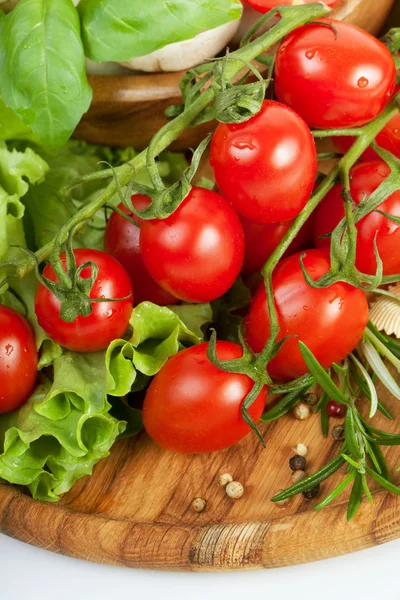 Fresh cherry tomatoes and salad in a wooden plate — Stock Photo, Image