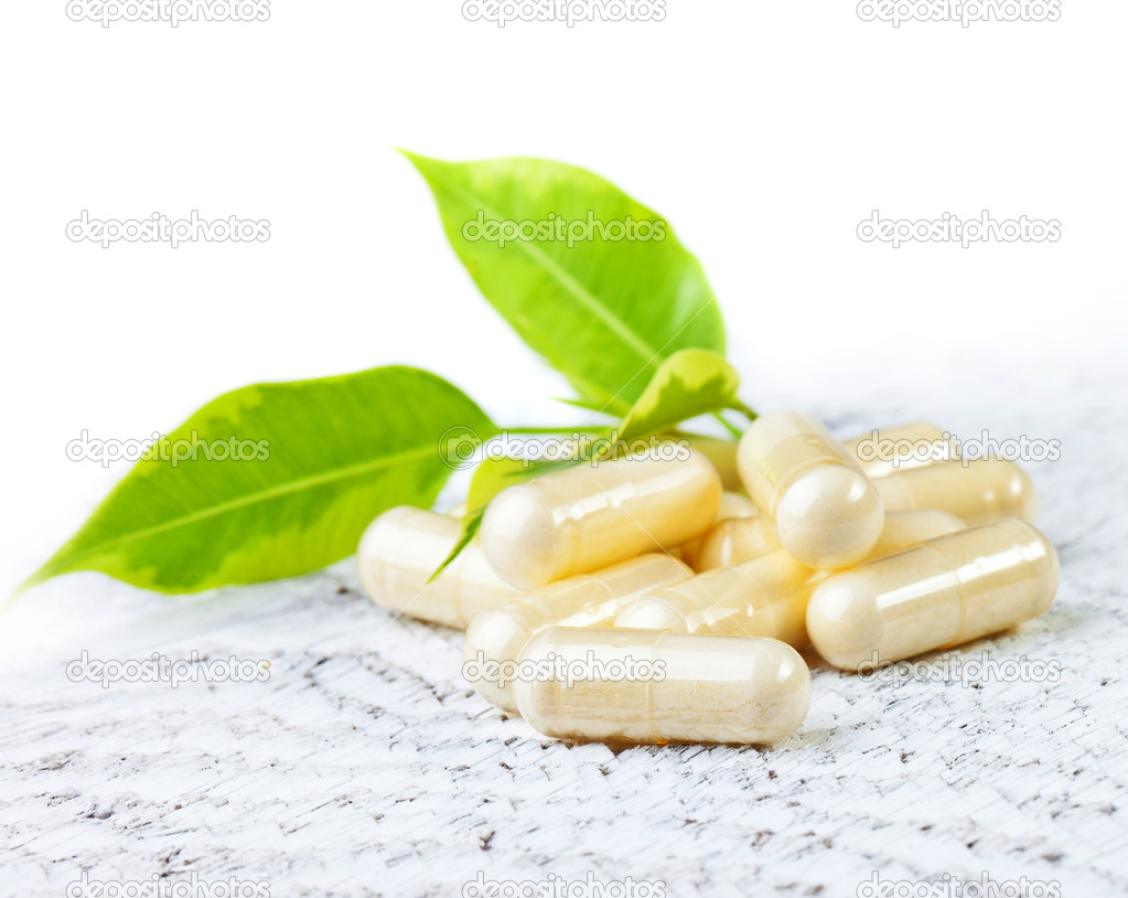 Capsules on wooden background.