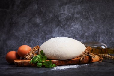 Çiğ hamur hamuru, un kaplı mutfak masasında havluyla kaplı bir kase, tarif fikri. Ev yapımı ya da hamur işi kavramını.