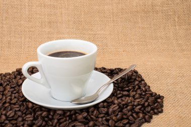 Tasty Coffee with coffee beans on background