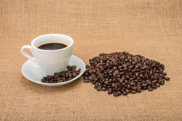 Leckerer Kaffee mit Kaffeebohnen im Hintergrund — Stockfoto