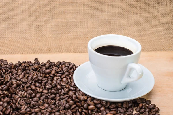 Leckerer Kaffee mit Kaffeebohnen im Hintergrund — Stockfoto