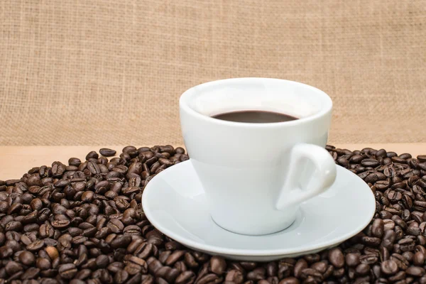Cafea gustoasă cu boabe de cafea pe fundal — Fotografie, imagine de stoc