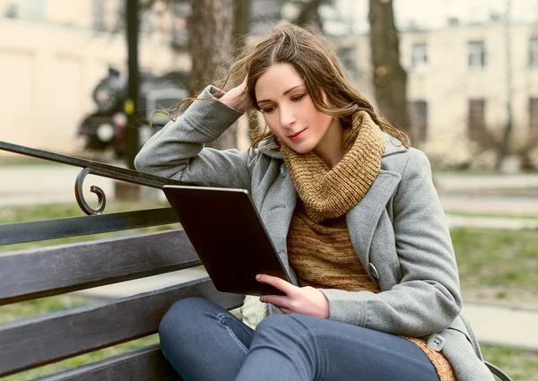 Jonge vrouw zitten met Tablet PC en lezen — Stockfoto
