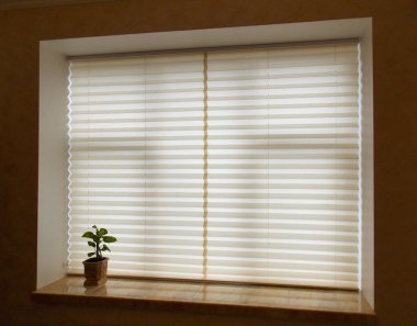 Pleated blinds XL, beige color, with 50mm fold closeup in the window opening in the interior. Home blinds - modern bottom up privacy shades on apartment windows. Closed.