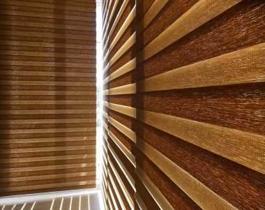 Çift tekerlekli perdeler iç taraftaki pencereye yakın çekim yapıyor. Balkonda çift tekerlekli paten bej rengi. Zebra kör eder.