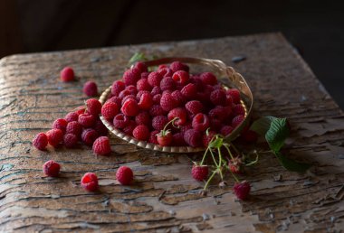 Yapraklı ahududu böğürtlenleri eski ahşap bir masada bakır antika bir tabakta kapanıyor. Ahududulu kırsal yaşam. Ağustos hasatı.