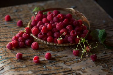 Yapraklı ahududu böğürtlenleri eski ahşap bir masada bakır antika bir tabakta kapanıyor. Ahududulu kırsal yaşam. Ağustos hasatı.