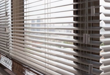 Alüminyum panjurlar. Metalden yapılmış. Venedik perdeleri pencereyi kapatıyor. Gümüş rengi. Şehir manzarası arka planda..