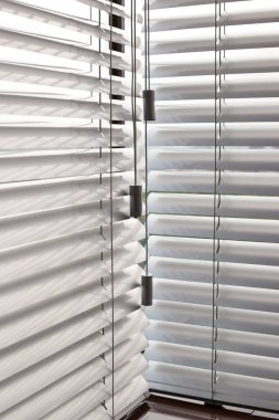 Ofis pencerelerinde alüminyum panjurlar var. Metalden yapılmış. Venedik perdeleri pencereyi kapatıyor. Gümüş rengi. Güneşli bir günde yatay jaluziler kapalı. Modern güneş koruması ve pencere dekorasyonu.