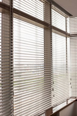 Alüminyum panjurlar. Metalden yapılmış. Venedik perdeleri pencereyi kapatıyor. Gümüş rengi. Şehir manzarası arka planda..