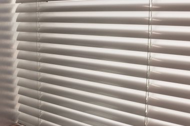 Alüminyum panjurlar. Metalden yapılmış. Venedik perdeleri pencereyi kapatıyor. Gümüş rengi. Güneşli bir günde kapalı yatay panjurlar.