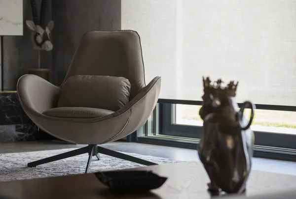 Interior design with roller blinds in the background. Automatic solar shades of large sizes on the window. Fabric with linen texture. In front of a large window is a chair on a carpet. 