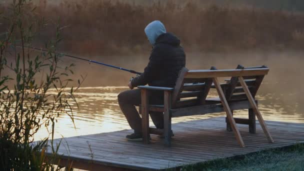 Man som håller i fiskespö sittandes på älven — Stockvideo