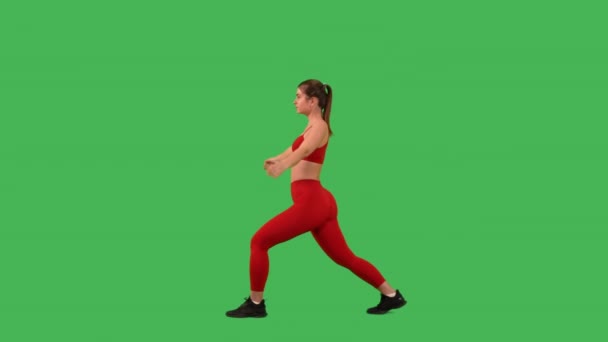 身材苗条的女人伸展和热身腿肌肉被绿色屏风隔开 身穿红色运动上衣和腿 — 图库视频影像