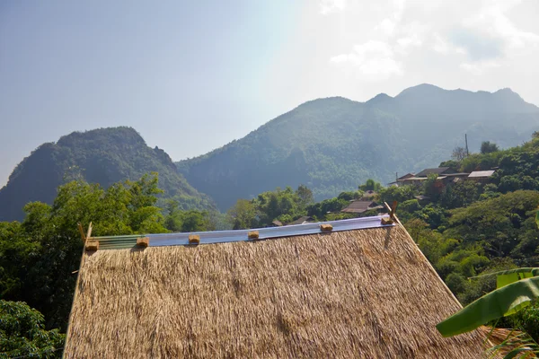 Roof hut made of dry grass. With a mountain background. — Stock Photo, Image
