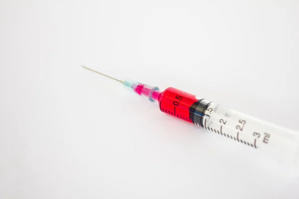 Syringe with red liquid on white background (Focus on red liquid — Stock Photo, Image