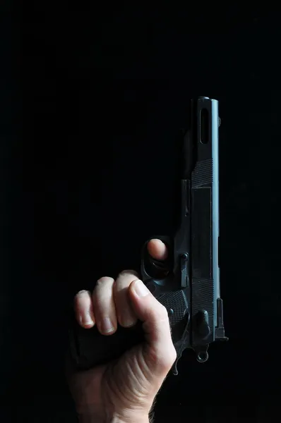 Pistola e uma mão em um fundo preto — Fotografia de Stock