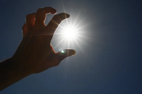 En hand fånga solstjärnorna på en blå bakgrund — Stockfoto