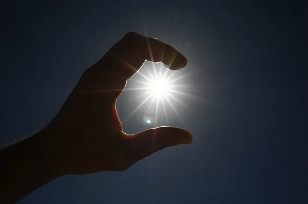 En hand fånga solstjärnorna på en blå bakgrund — Stockfoto