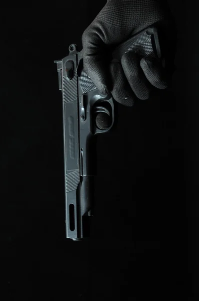 Pistola e uma mão em um fundo preto — Fotografia de Stock