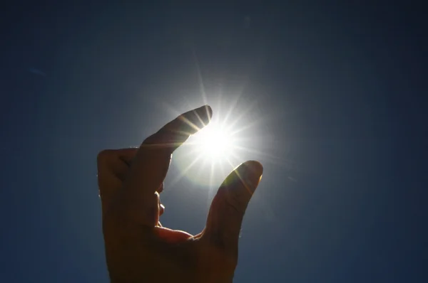 En hand fånga solstjärnorna på en blå bakgrund — Stockfoto