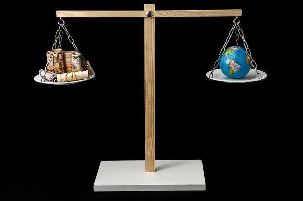 Земля и деньги на двухкамерном балансе — стоковое фото