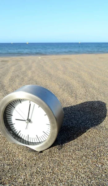 海の近くのビーチで砂の上の古典的なアナログ時計 — ストック写真