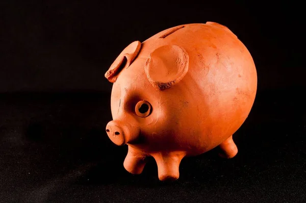 piggy bank made with red ceramic on a black background