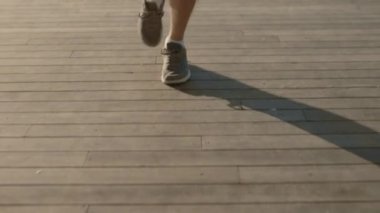 Erkek bacakları spor ayakkabılarla dışarıda koşuyor.