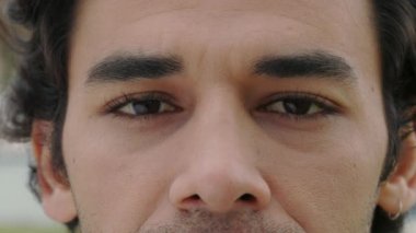 Açık havada poz veren yakışıklı Arap adamın yakın portresi.