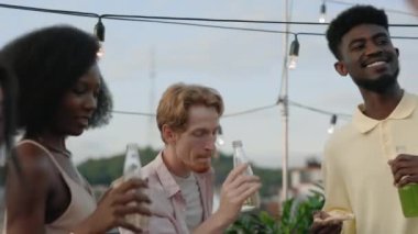 Genç kızıl saçlı adam partide karışık ırk arkadaşlarıyla rahatlıyor.