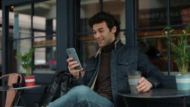 Arab srác ül a kávézóban okostelefonnal és kávéval — Stock videók