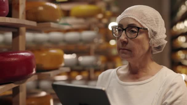 Пожилая женщина с планшетом, изучающая состояние головок сыра — стоковое видео