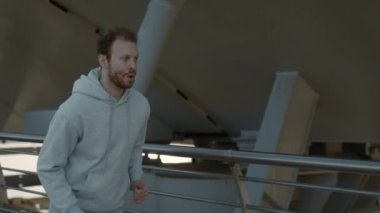 Spor giyim sektöründe aktif genç adam şehir merkezinde koşuyor.