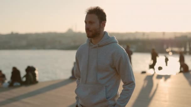 Портрет чоловічої бігунки в светрі, що стоїть біля міської річки — стокове відео