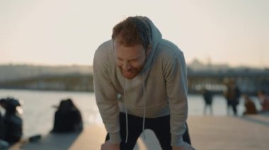 Spor kıyafetleri içinde yorgun bir adam akşam koşusundan sonra dinleniyor.