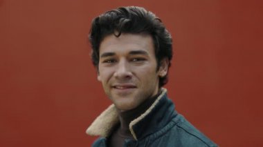 Arap adam sokakta dikiliyor ve kameraya gülümsüyor.