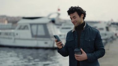 İskelede yürürken akıllı telefon kullanan Arap bir adam.