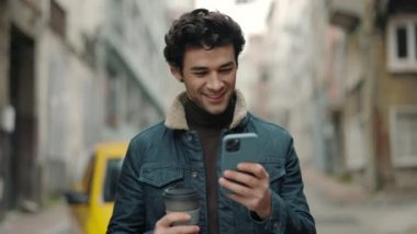 Cep telefonu kullanan ve sokakta kahve içen Arap turist.