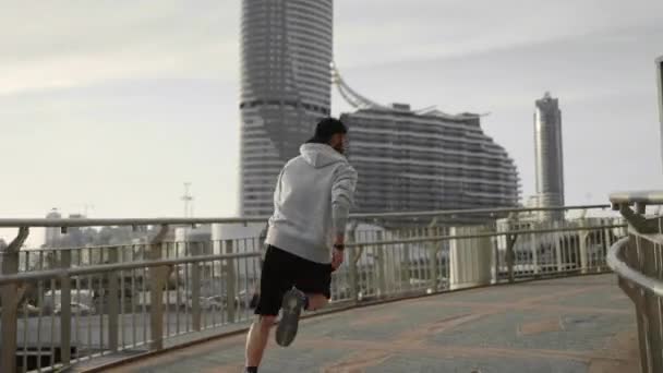 Uomo muscoloso in abiti sportivi in esecuzione sulla strada della città — Video Stock