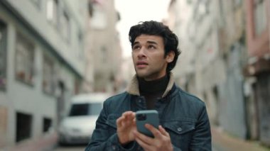 Yeni şehirde yürürken akıllı telefon kullanan Arap turist