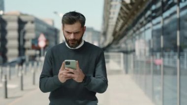 Resmi giyinmiş olgun bir adam şehir caddesinde cep telefonu kullanıyor.